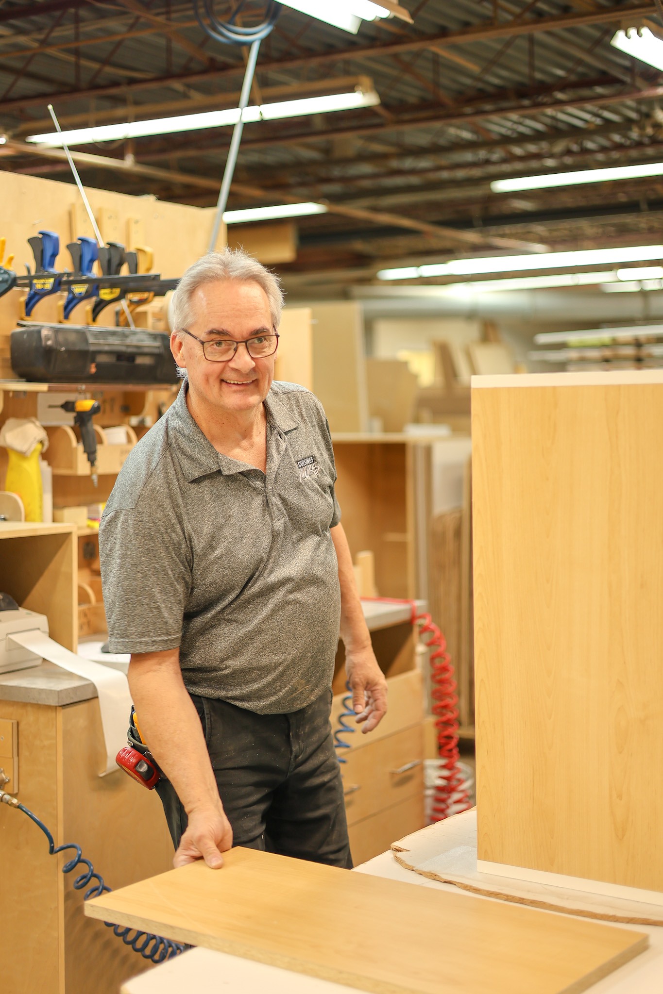 Un employé de l’usine porte une planche de bois et sourit à la caméra