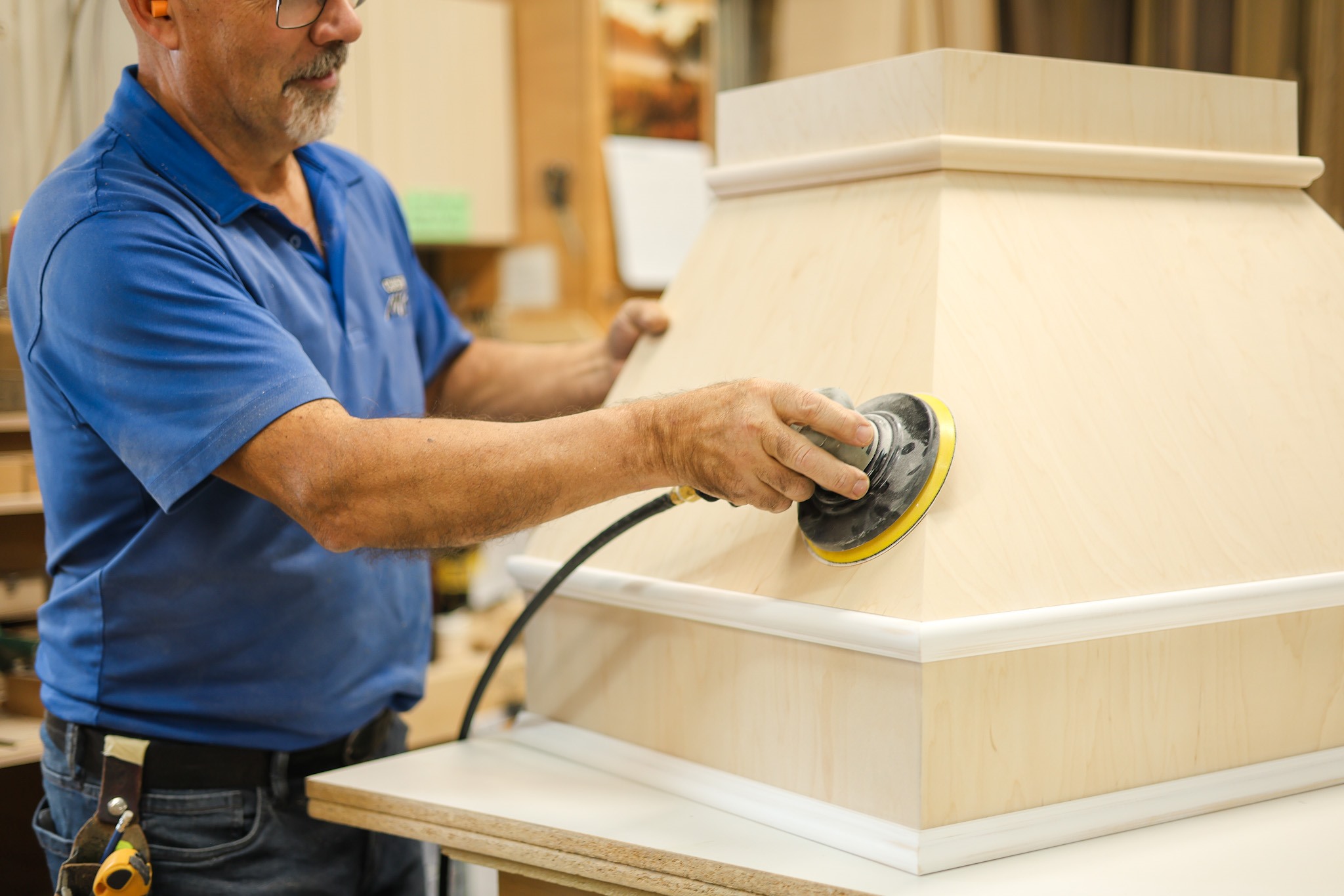 Un employé ponce à la main la pièce en bois d’une hotte