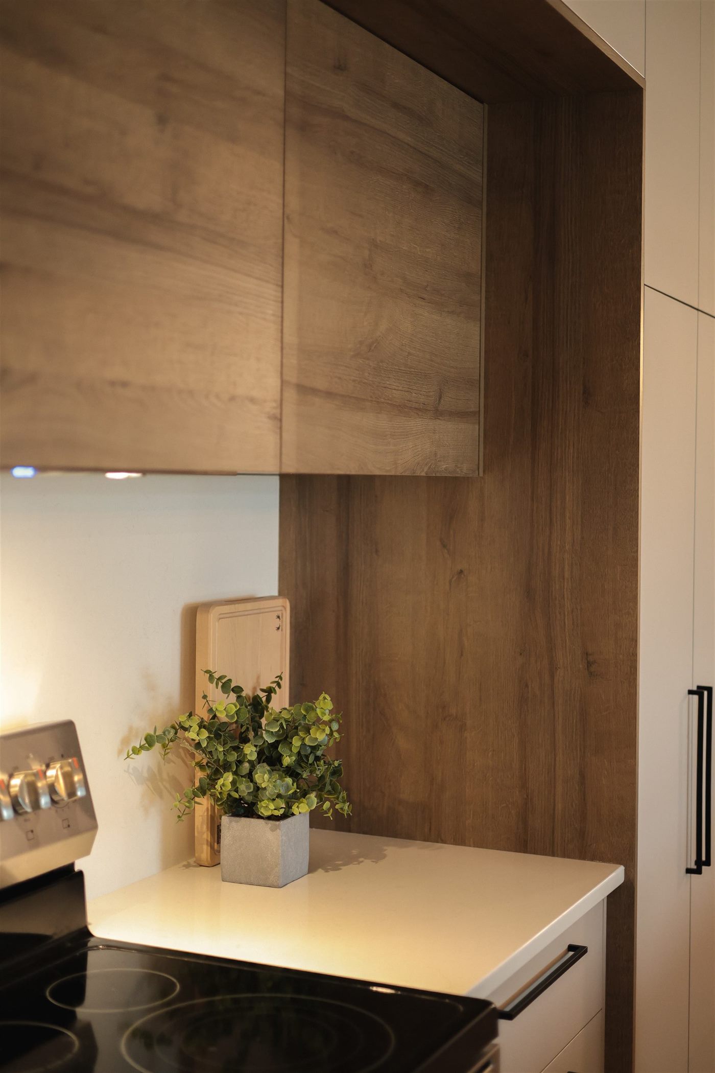 La Vitrine : Armoires taupe pleine hauteur, garde-manger vitré et étagère ouverte en noyer, comptoir de quartz blanc