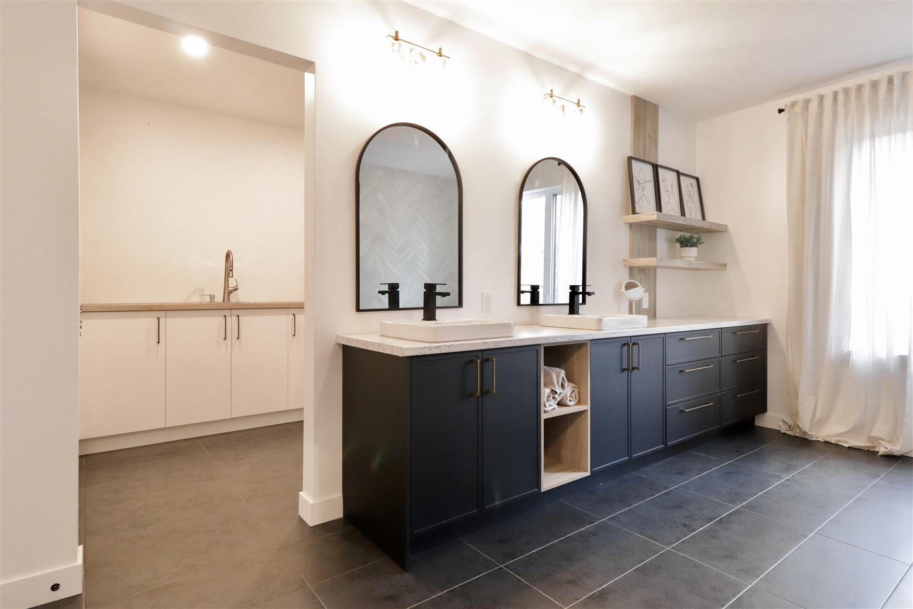 L’Arche : Vanité double noire, miroirs arqués et étagères flottantes en bois, sous un éclairage doré