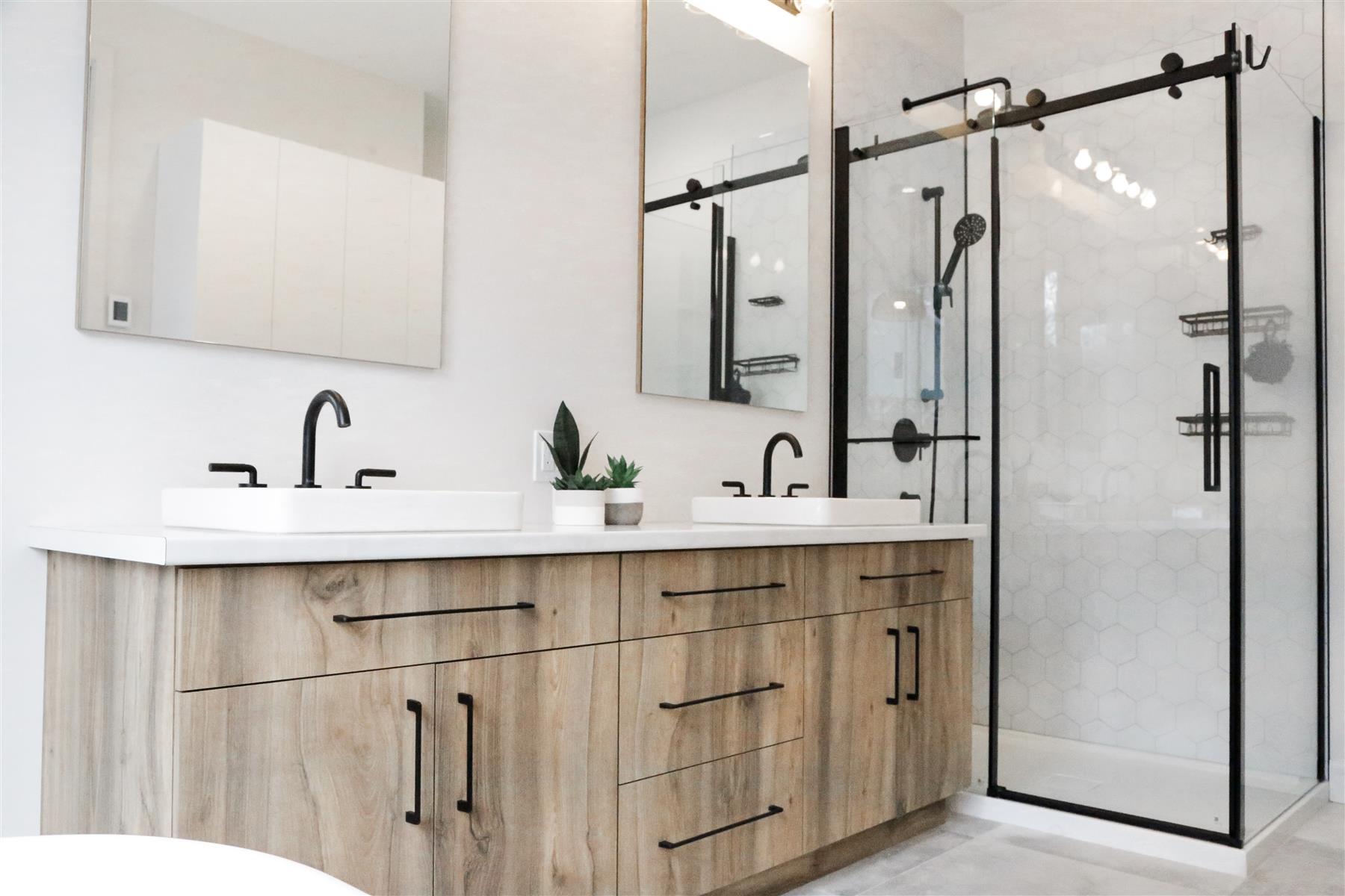 La Source : Vanité double en bois naturel, quincaillerie noire et douche à portes coulissantes en hexagones blancs
